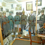 Overview of a museum showcase with soldier uniforms and historical documents from the First World War